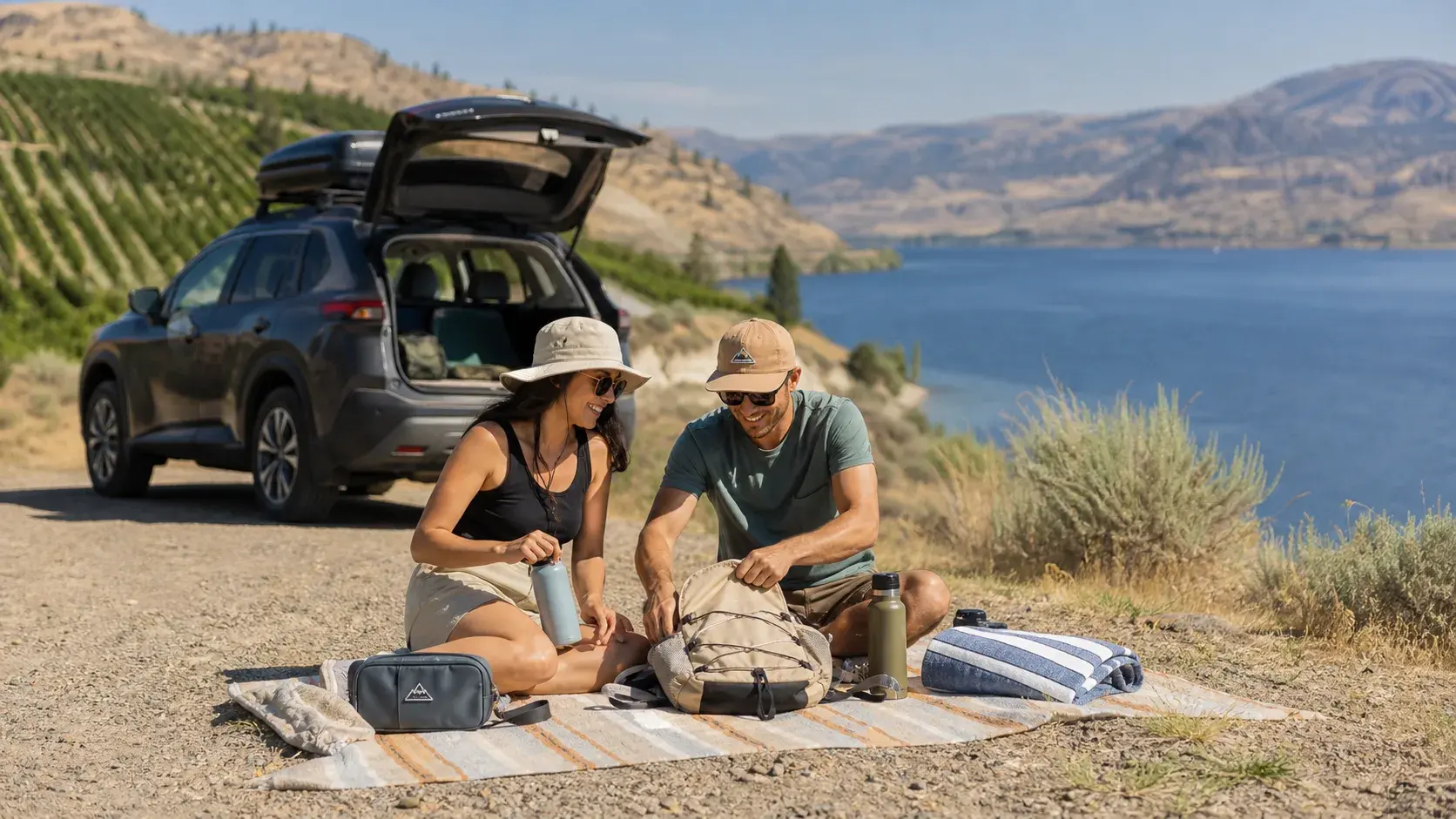 Travellers preparing water, towels and a day bag at an Okanagan lake-view picnic pullout beside a safely parked car