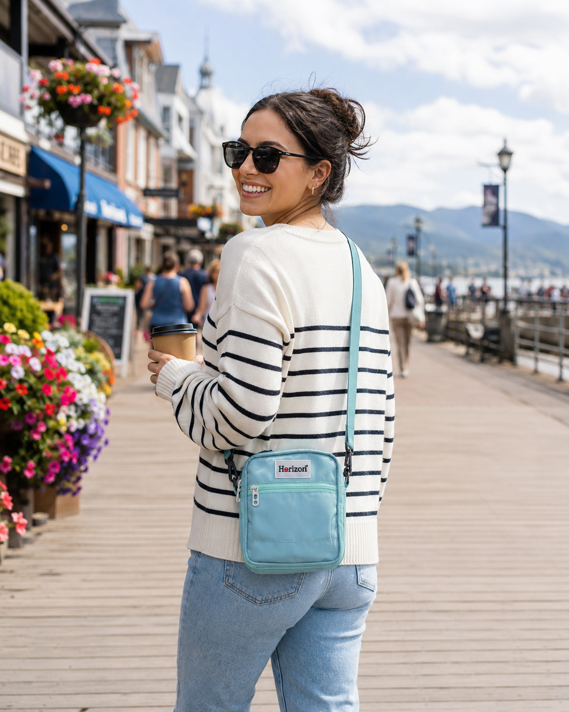 Blue Horizon Toastie Crossbody Bag worn on a lake town boardwalk near shops and mountain views